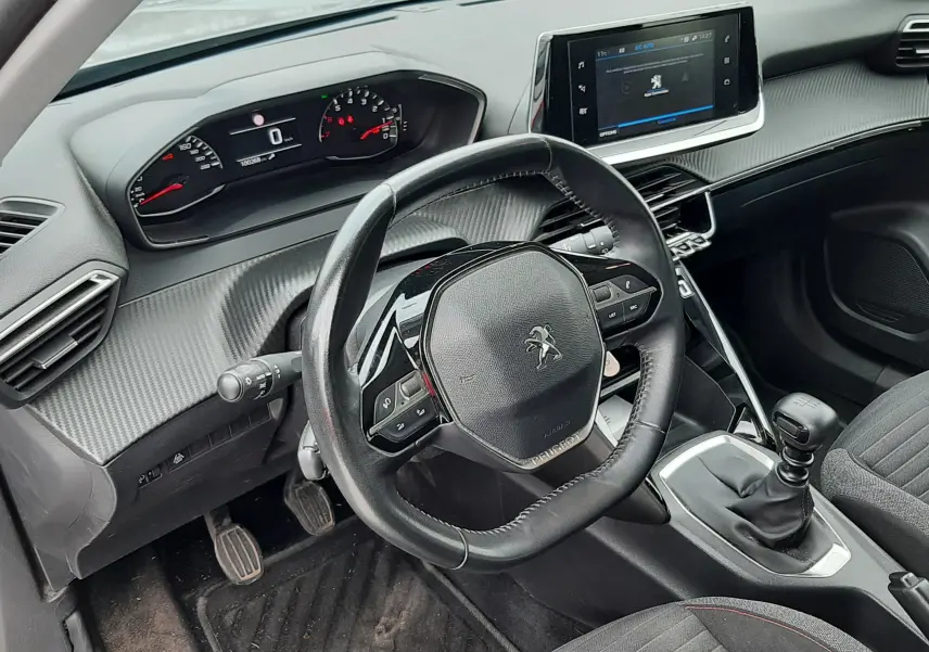 Vue intérieure côté conducteur du Peugeot 2008 2020, tableau de bord avec volant compact, écran tactile et levier de vitesse manuel.