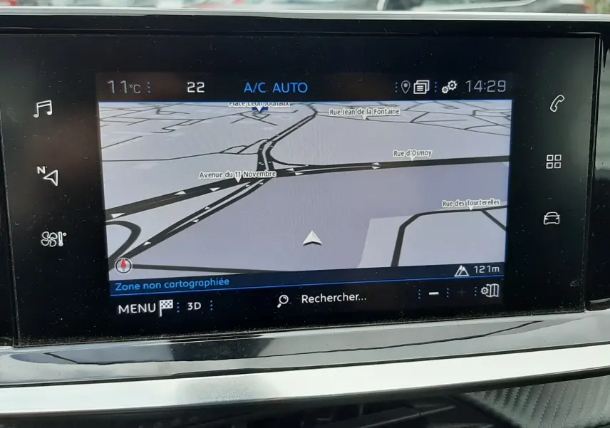 Vue intérieure centrée sur l'écran tactile du GPS du Peugeot 2008 gris Artense, avec un véhicule flou en arrière-plan.