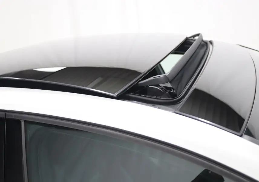 Détail du toit panoramique ouvert sur une Volkswagen Golf blanche, vue côté gauche avec vitre teintée.