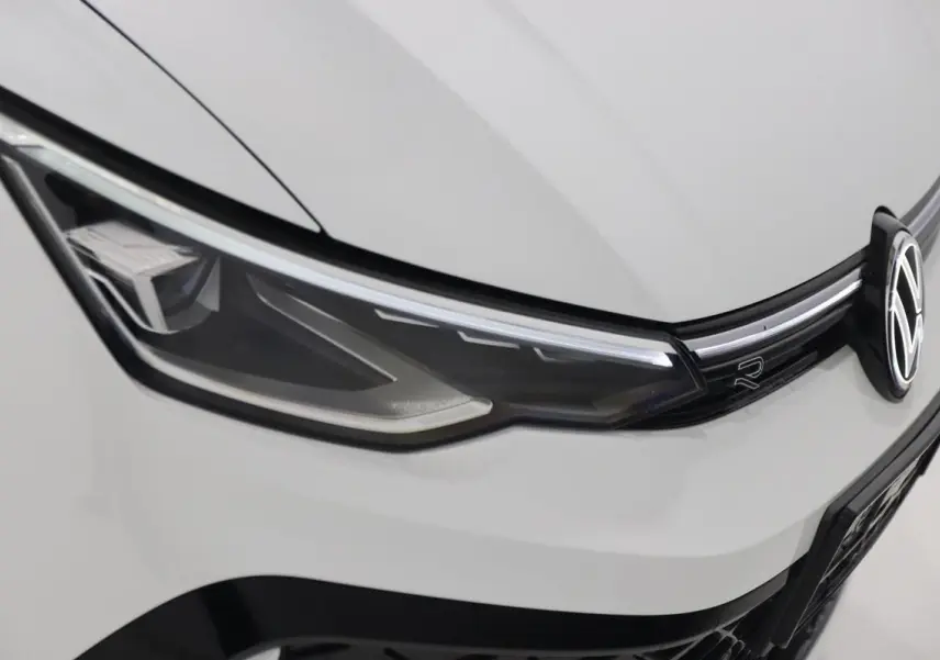 Gros plan sur le phare avant gauche et la calandre blanche d'une Volkswagen Golf 2.0 TDI R-Line 2025.