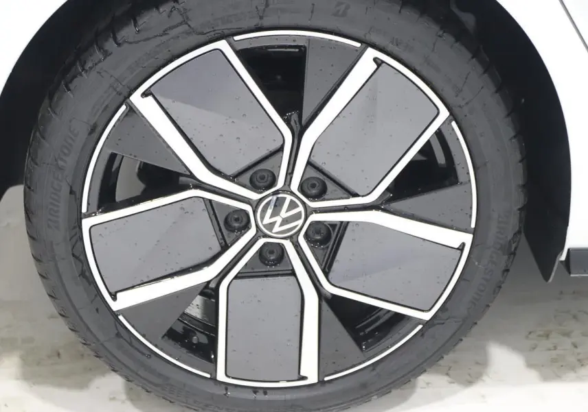 Gros plan sur la jante alliage noire et argentée de la Volkswagen Golf blanche, côté roue avant droite.