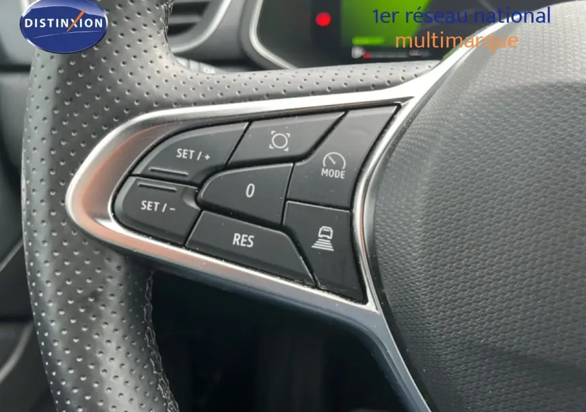 Gros plan sur les commandes de régulateur au volant en cuir perforé d'une Renault Symbioz gris cassiopée metal.