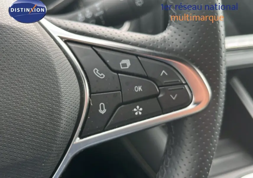 Gros plan sur les commandes multifonctions à gauche du volant perforé du Renault Symbioz gris Cassiopée métal.