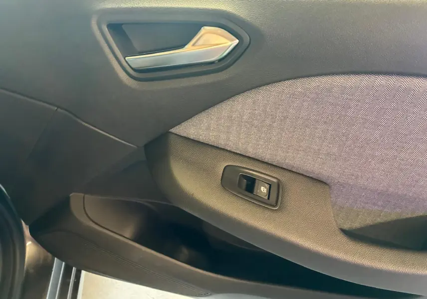 Détail de la porte côté gauche de la Renault Clio 2025 gris schiste, avec poignée argentée et bouton de commande de vitre.