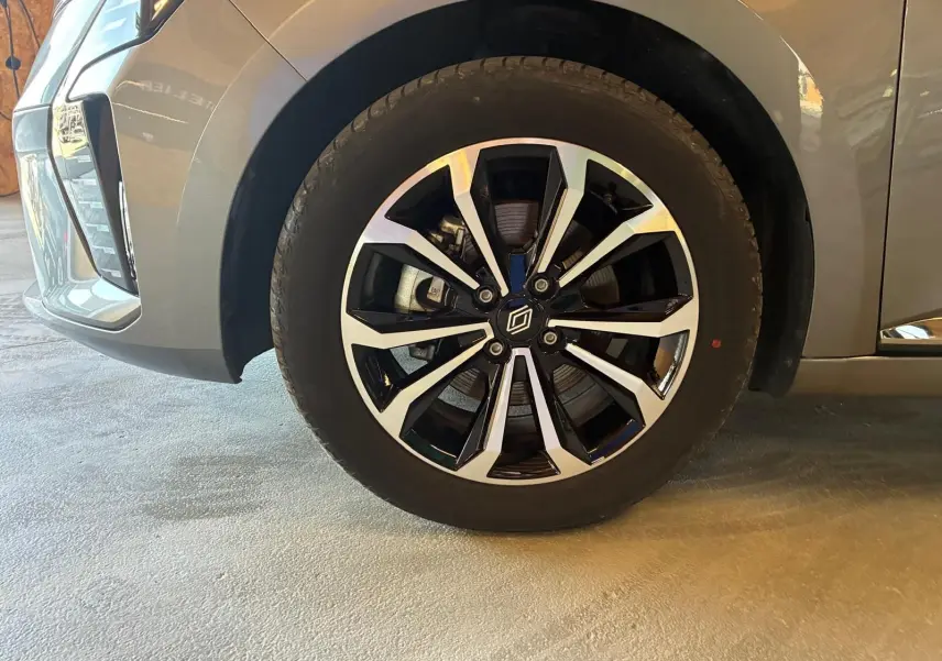 Gros plan sur la roue avant gauche de la Renault Clio gris schiste, mettant en valeur la jante alliage bicolore au design moderne.