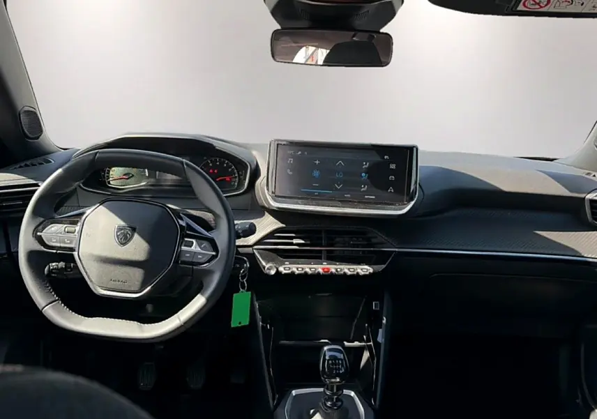 Intérieur de la Peugeot 2008 1.2 100 style 2025, vue frontale du tableau de bord avec écran tactile et volant multifonction.