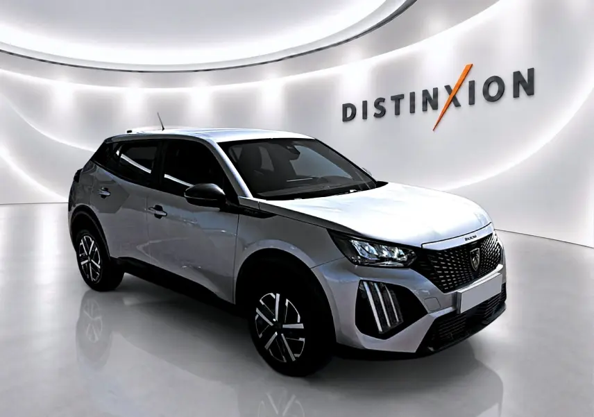 Peugeot 2008 gris en 3/4 avant droit dans un showroom lumineux avec calandre noire distinctive et jantes stylisées.