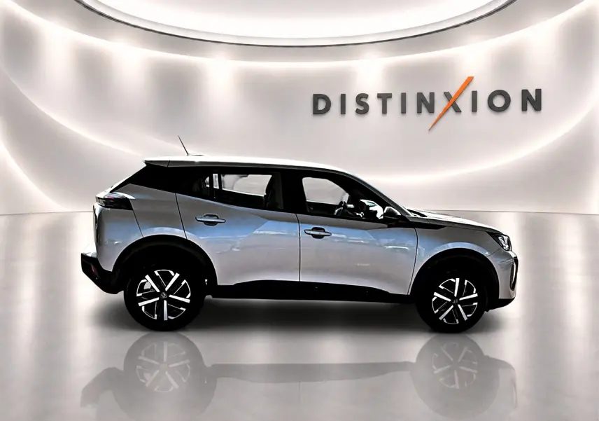 Peugeot 2008 gris en profil droit dans un showroom lumineux avec jantes noires et toit noir contrastant.
