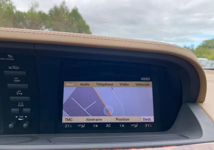 Écran de navigation central avec affichage cartographique dans le tableau de bord en cuir beige d'une Mercedes Classe S noire.