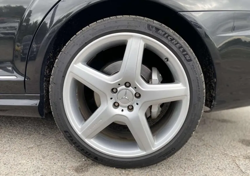 Gros plan sur la jante alliage AMG 5 branches argentée de la roue avant gauche d'une Mercedes Classe S noire.