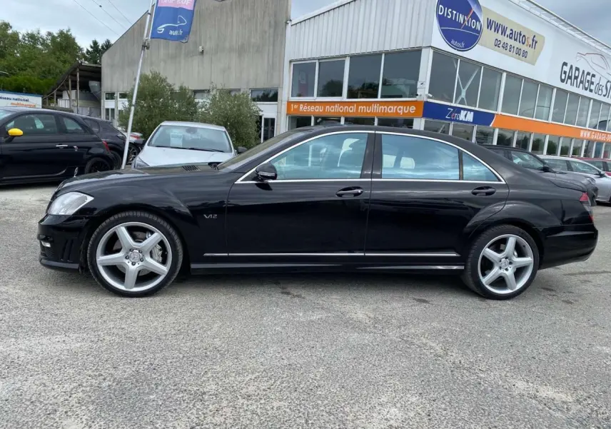 Profil côté gauche d'une Mercedes Classe S 600 L noire avec jantes AMG 20 pouces et badge V12 visible.