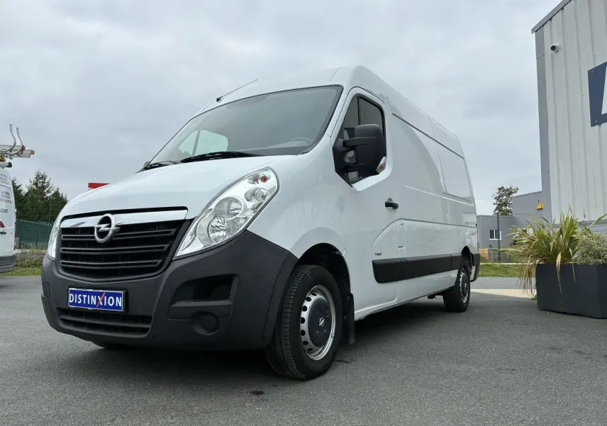 Fourgon Opel Movano blanc vu en 3/4 avant droit, avec pare-chocs noir et jantes acier, stationné sur un parking.