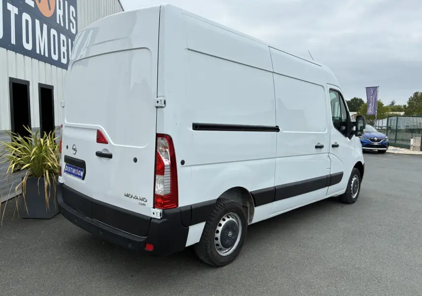 Opel Movano Fourgon blanc vu en 3/4 arrière droit, avec bande noire latérale et feux arrière rouges.