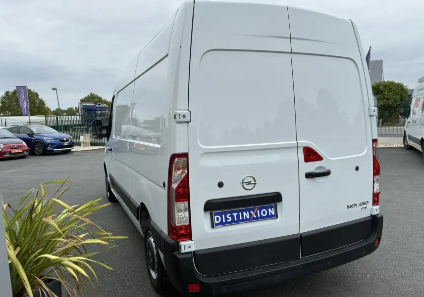 Vue arrière droite d'un fourgon blanc Opel Movano 2.3 CDTI 130 L2H2 avec logo et plaque Distinxion visible.
