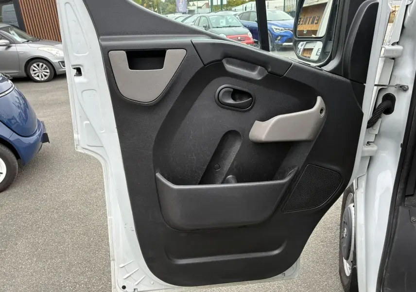Vue rapprochée de la porte côté gauche ouverte d'un Opel Movano Fourgon blanc, avec panneau intérieur noir et poignée grise.