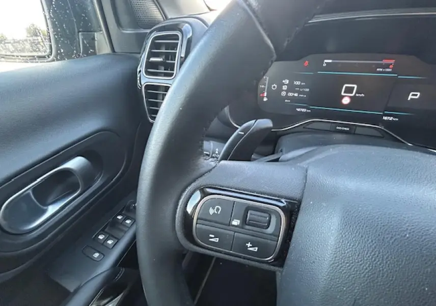 Vue rapprochée du volant et tableau de bord numérique du Citroën C5 Aircross 2022 en intérieur noir.