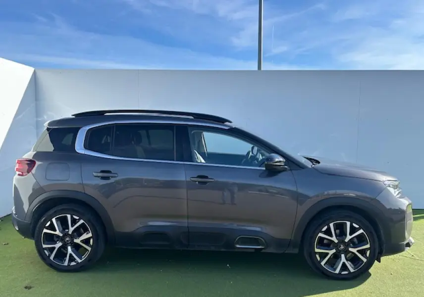 Profil droit d'un Citroën C5 Aircross gris platinium 2022 avec barres de toit et jantes alliage noires et argentées.