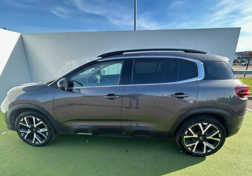 Profil côté gauche du SUV Citroën C5 Aircross gris platinium 2022 avec jantes alliage et barres de toit noires.