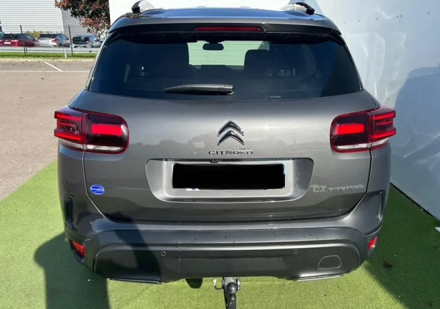 Vue arrière d'un Citroën C5 Aircross gris platinium avec attelage et feux arrière LED visibles.