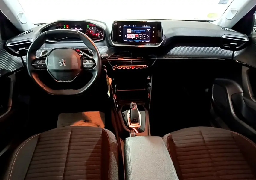 Vue intérieure avant du Peugeot 2008 2021, tableau de bord noir avec volant cuir multifonctions et écran tactile central.