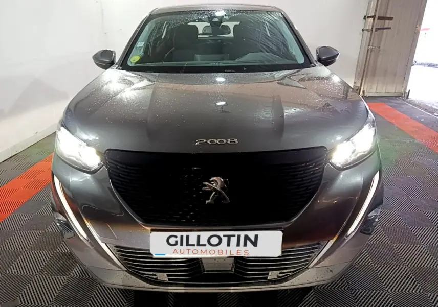 Vue avant d'un Peugeot 2008 gris clair avec phares allumés et calandre noire distinctive.