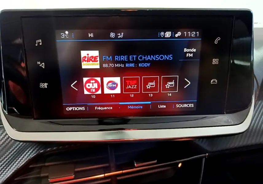 Écran tactile central du tableau de bord du Peugeot 2008 gris clair, affichant les stations radio FM.