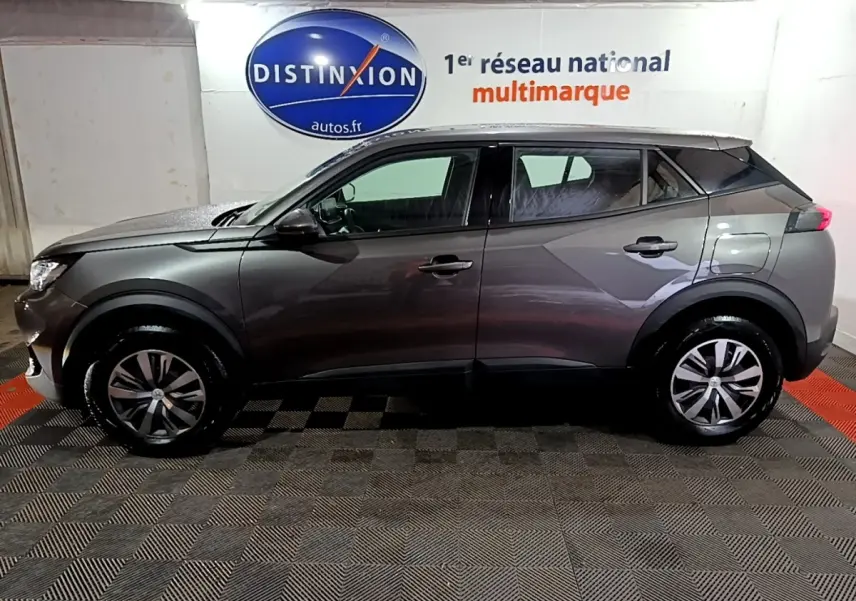 Profil droit du Peugeot 2008 gris clair 2021 garé en intérieur avec jantes alliage et vitres teintées.