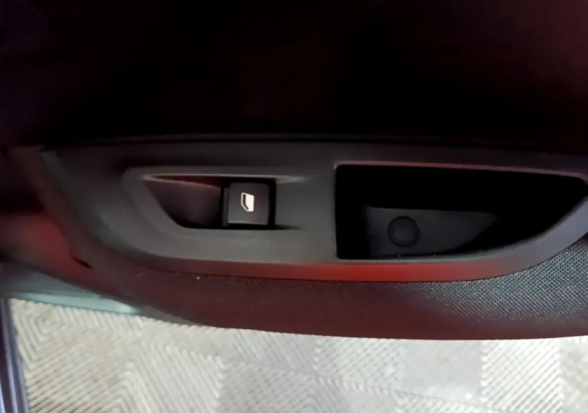 Bouton de commande de lève-vitre côté conducteur sur la porte intérieure d’un Peugeot 2008 gris clair.