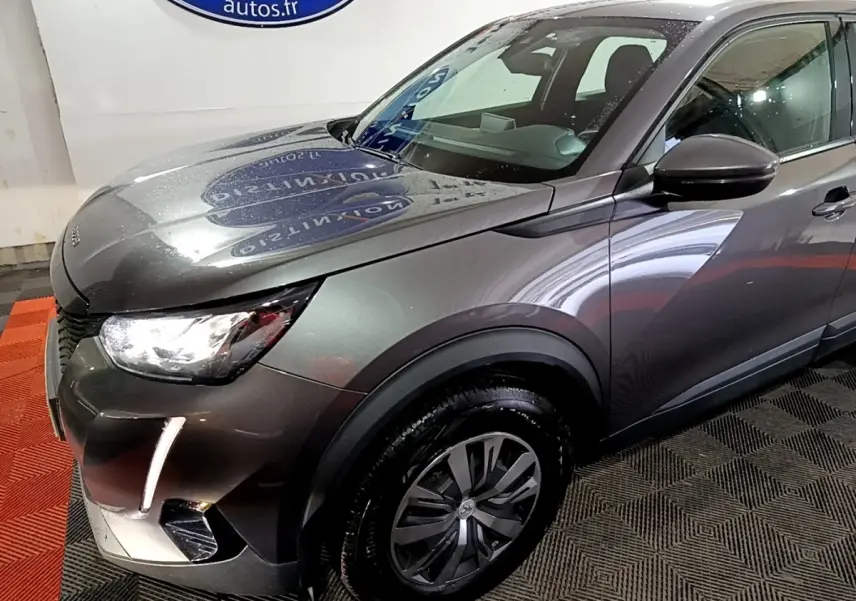 Vue 3/4 avant droit d'un Peugeot 2008 gris clair avec feux LED et jantes alliage distinctives.