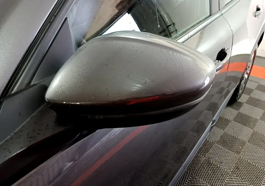 Gros plan sur le rétroviseur côté gauche gris clair du Peugeot 2008, avec reflet de l'environnement intérieur.