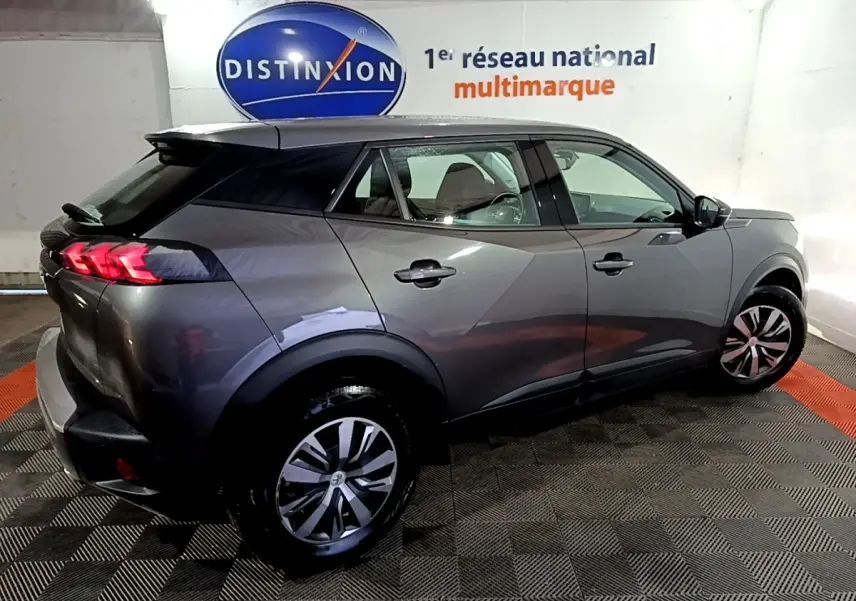 Peugeot 2008 gris clair vue 3/4 arrière droit en intérieur, avec feux arrière LED et jantes alliage.