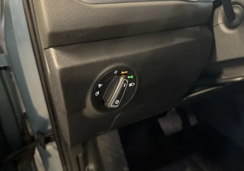 Gros plan sur le bouton de commande des phares à gauche du volant dans l’habitacle bleu du Volkswagen T-Roc 2022.