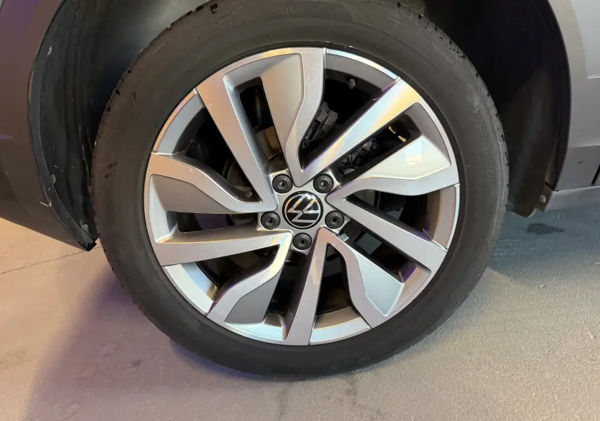 Gros plan sur la jante alliage argentée du Volkswagen T-Roc bleu, mettant en valeur le logo VW central.