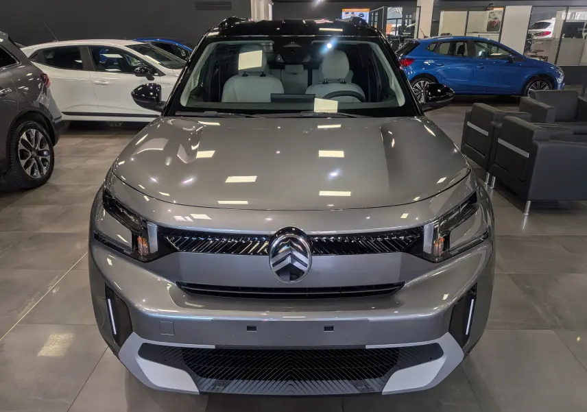 Vue frontale d'un Citroën C3 Aircross 2026 hybride gris Mercury avec toit noir en showroom.