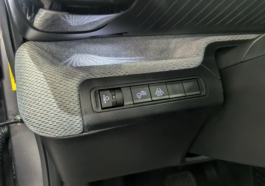 Vue rapprochée des commandes de réglage des phares et aides à la conduite sur le côté gauche intérieur d'une Citroën C3 Aircross gris Mercury.