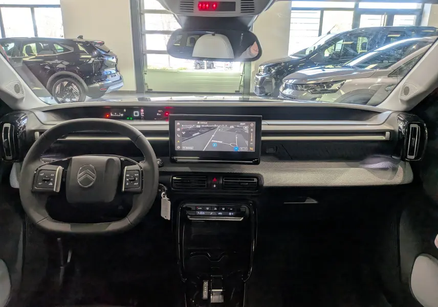 Vue intérieure frontale du tableau de bord du Citroën C3 Aircross hybride gris Mercury avec écran tactile central et volant multifonction.
