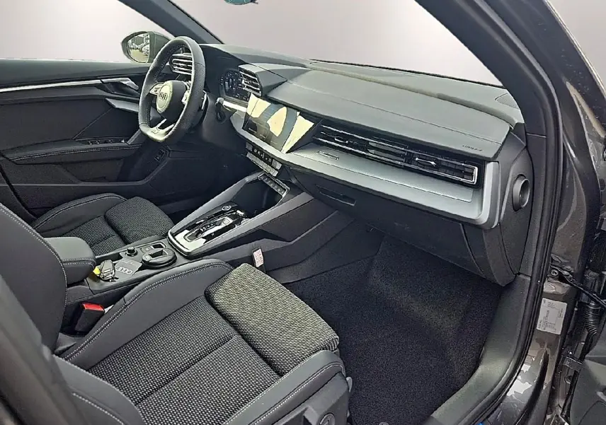 Intérieur avant droit d’Audi A3 Sportback gris Daytona, avec tableau de bord moderne et sièges sport noirs.
