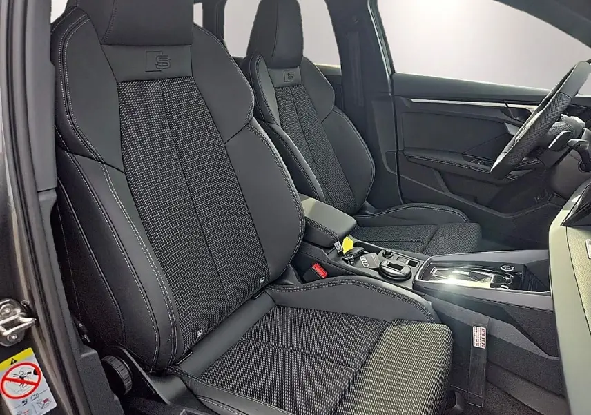 Vue intérieure côté gauche des sièges sport noirs avec surpiqûres blanches et logo S sur un Audi A3 Sportback 2026.