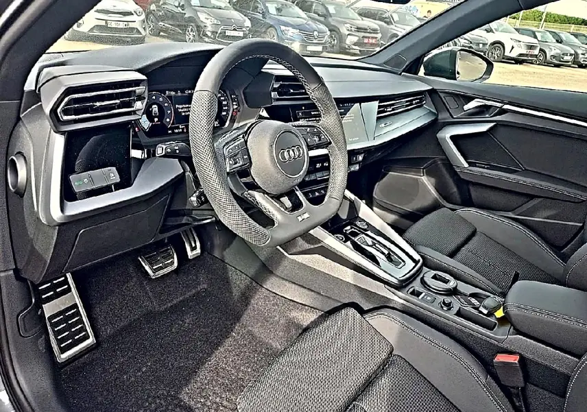 Vue intérieure côté conducteur de l'Audi A3 Sportback 2026, volant sport cuir et console centrale moderne noire.