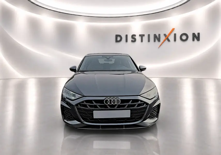 Audi A3 Sportback gris Daytona vue de face dans un showroom avec éclairage moderne et logo Distinxion en arrière-plan.