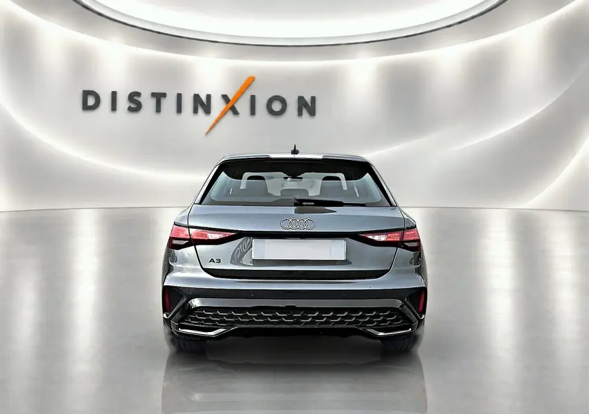 Vue arrière d'une Audi A3 Sportback gris Daytona dans un showroom lumineux avec logo Distinxion en arrière-plan.
