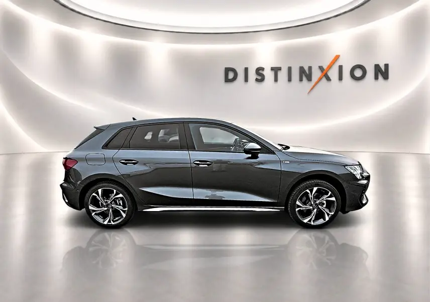 Audi A3 Sportback gris Daytona vue de profil droit, avec jantes alliage et toit noir contrasté dans un showroom lumineux.