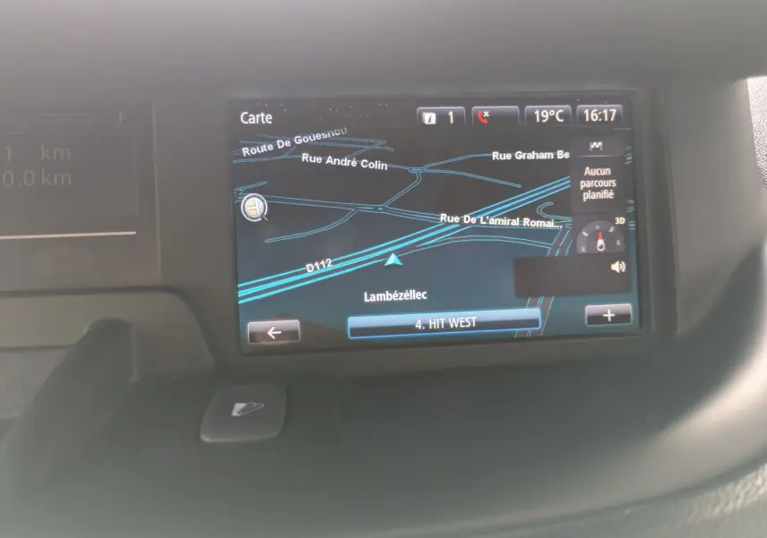 Écran de navigation GPS du Renault Scénic IV blanc, affichant une carte routière et les options de température et heure.