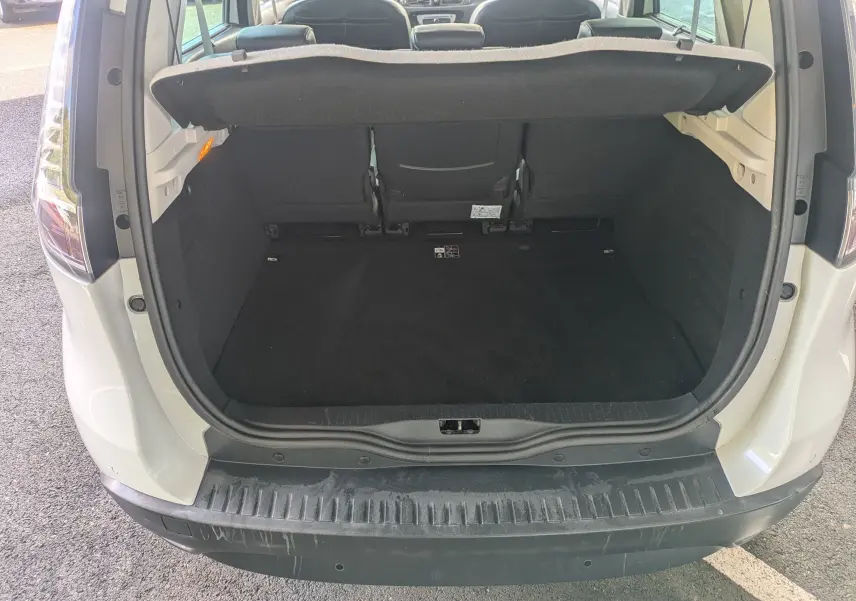 Coffre ouvert vu de l'arrière d'un Renault Scenic IV blanc, montrant l'espace de chargement et la banquette arrière.