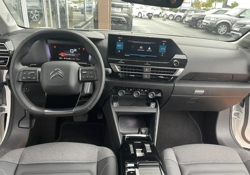 Intérieur de la Citroën C4 blanche 2022, vue frontale sur le tableau de bord avec écran tactile et volant multifonction.