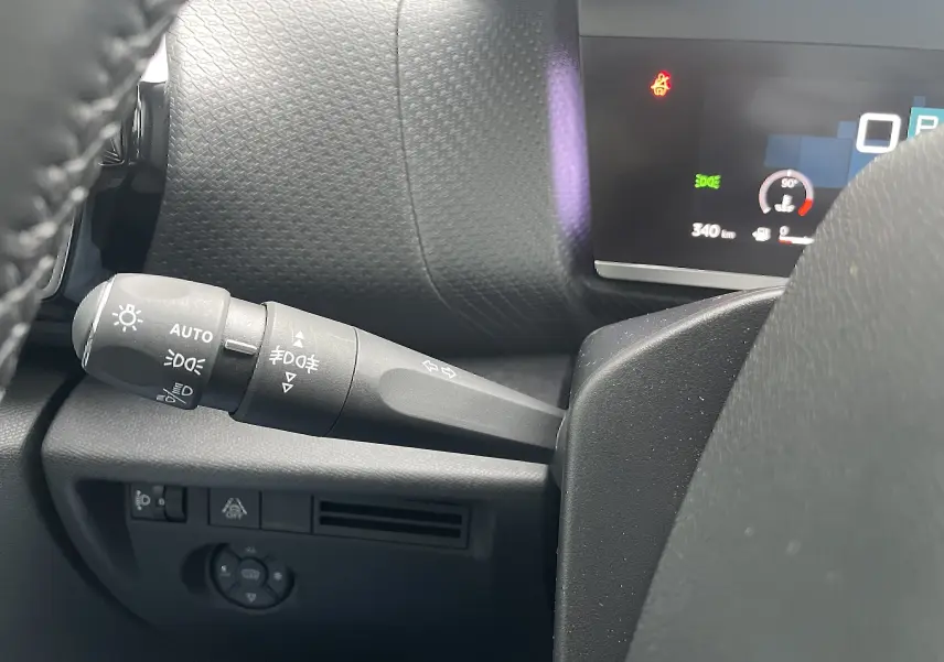 Gros plan sur la commande des feux et clignotants côté gauche du tableau de bord d’une Citroën C4 blanche 2022.