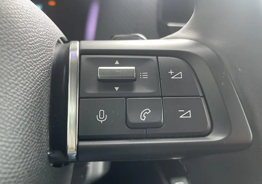 Gros plan sur les commandes au volant côté gauche d'une Citroën C4 blanche, boutons de volume et appel visibles.