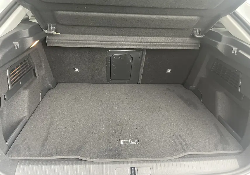 Coffre ouvert d'une Citroën C4 blanche 2022, vue intérieure montrant un tapis noir avec logo C4 et éclairage latéral.