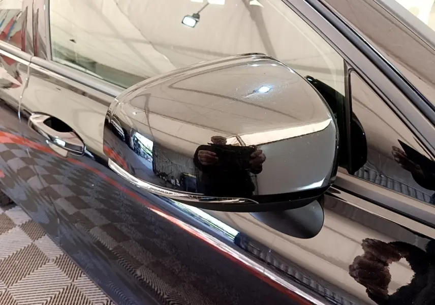 Gros plan sur le rétroviseur côté conducteur noir brillant d’un Volvo V60 D3 Business 2020 avec porte assortie.