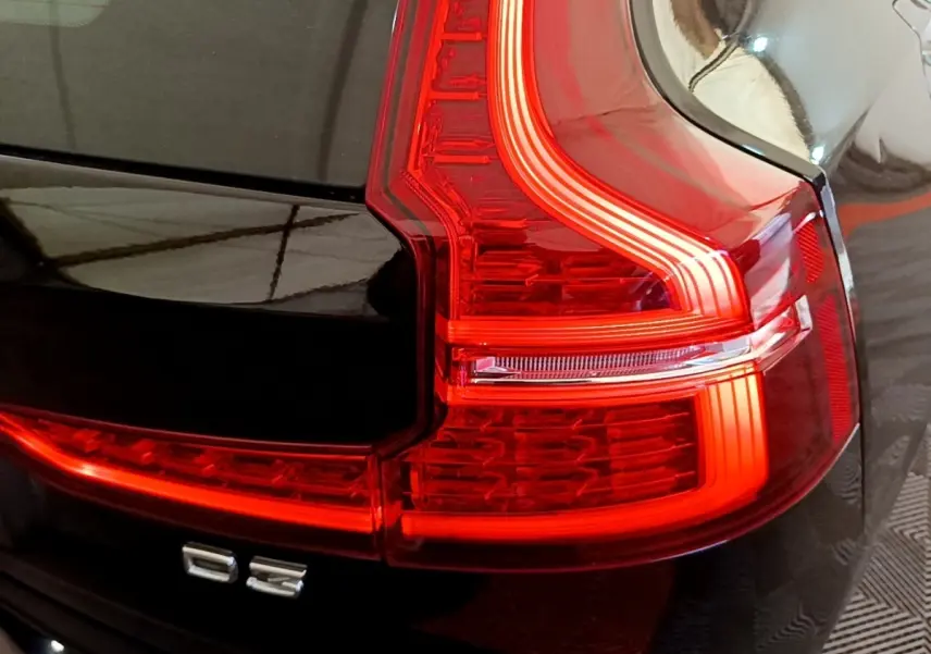 Gros plan sur le feu arrière droit rouge d’une Volvo V60 D3 noire, mettant en valeur le badge D3 et la carrosserie brillante.
